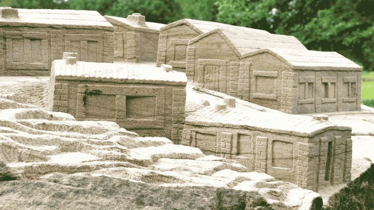 Close up image of the stone sculpture in the parkland focusing on the houses that people lived in.